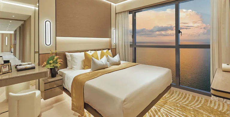 Coastal Cabana, artist&rsquo;s impression: a bedroom with a full-height window over the sea at sunset, in the developer&rsquo;s show-unit styling